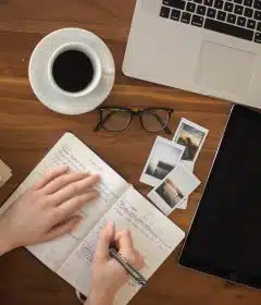 person holding ballpoint pen writing on notebook